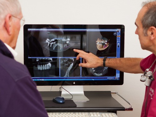 Zahnarzt zeigt einem Patienten digitale Röntgenaufnahmen am Bildschirm